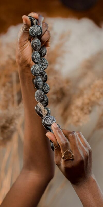 A close-up of hands holding a handcrafted beaded necklace against a soft background.