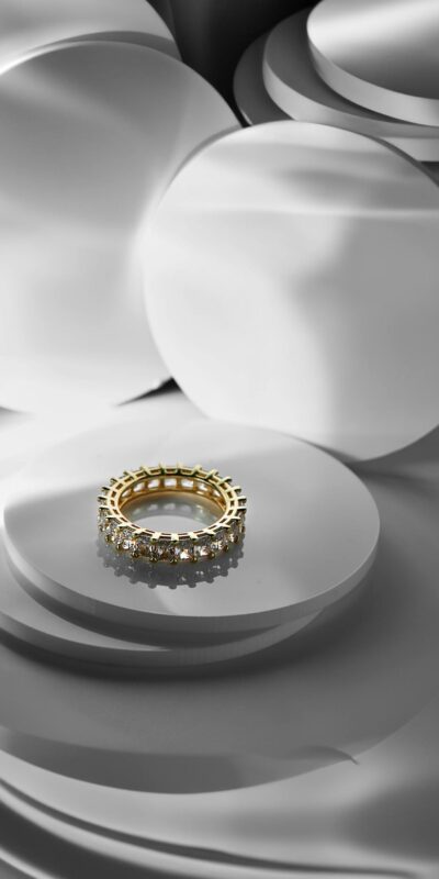 A luxurious diamond and gold ring displayed against a sleek, modern abstract background.