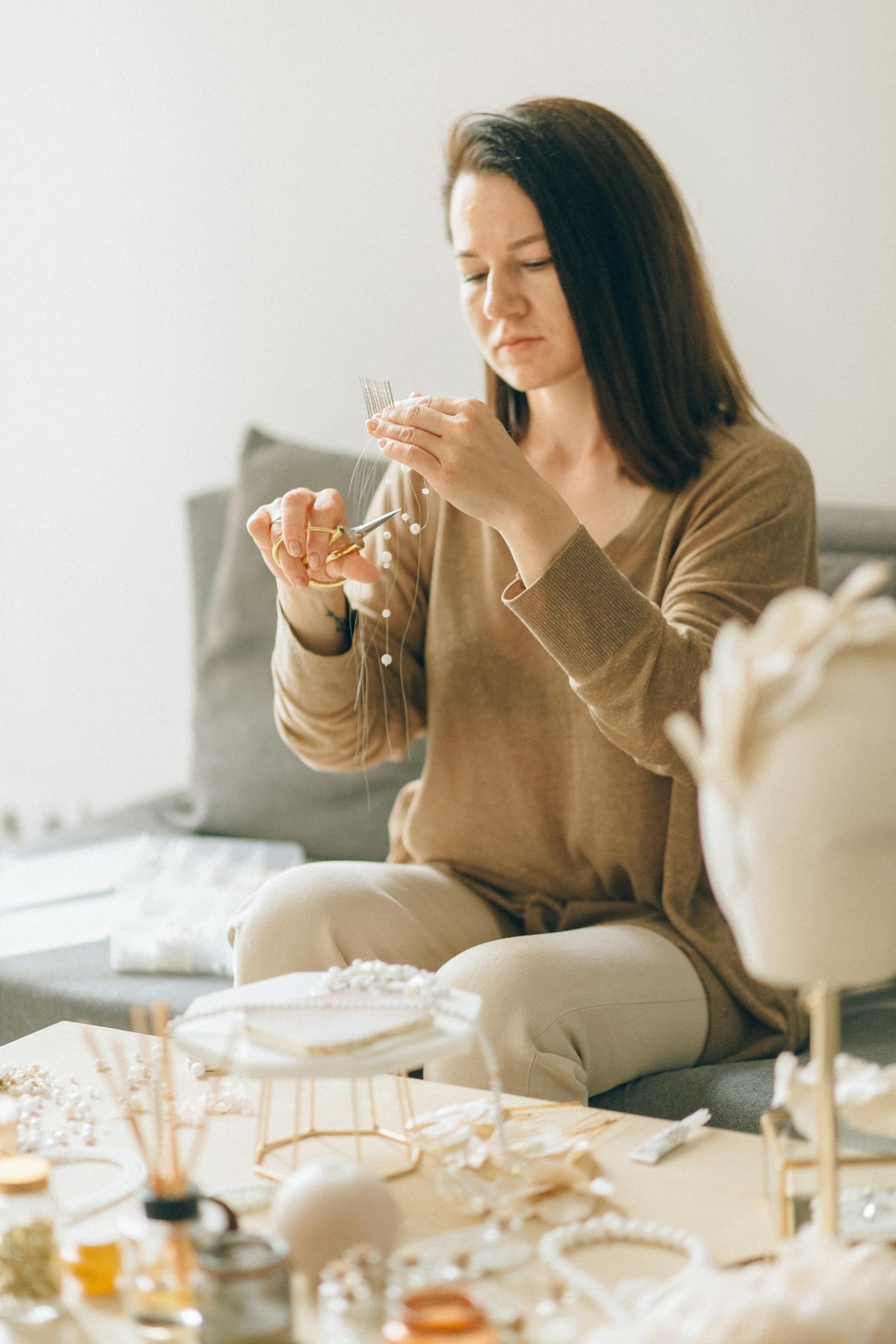 Adult woman focused on crafting handmade jewelry with beads indoors.