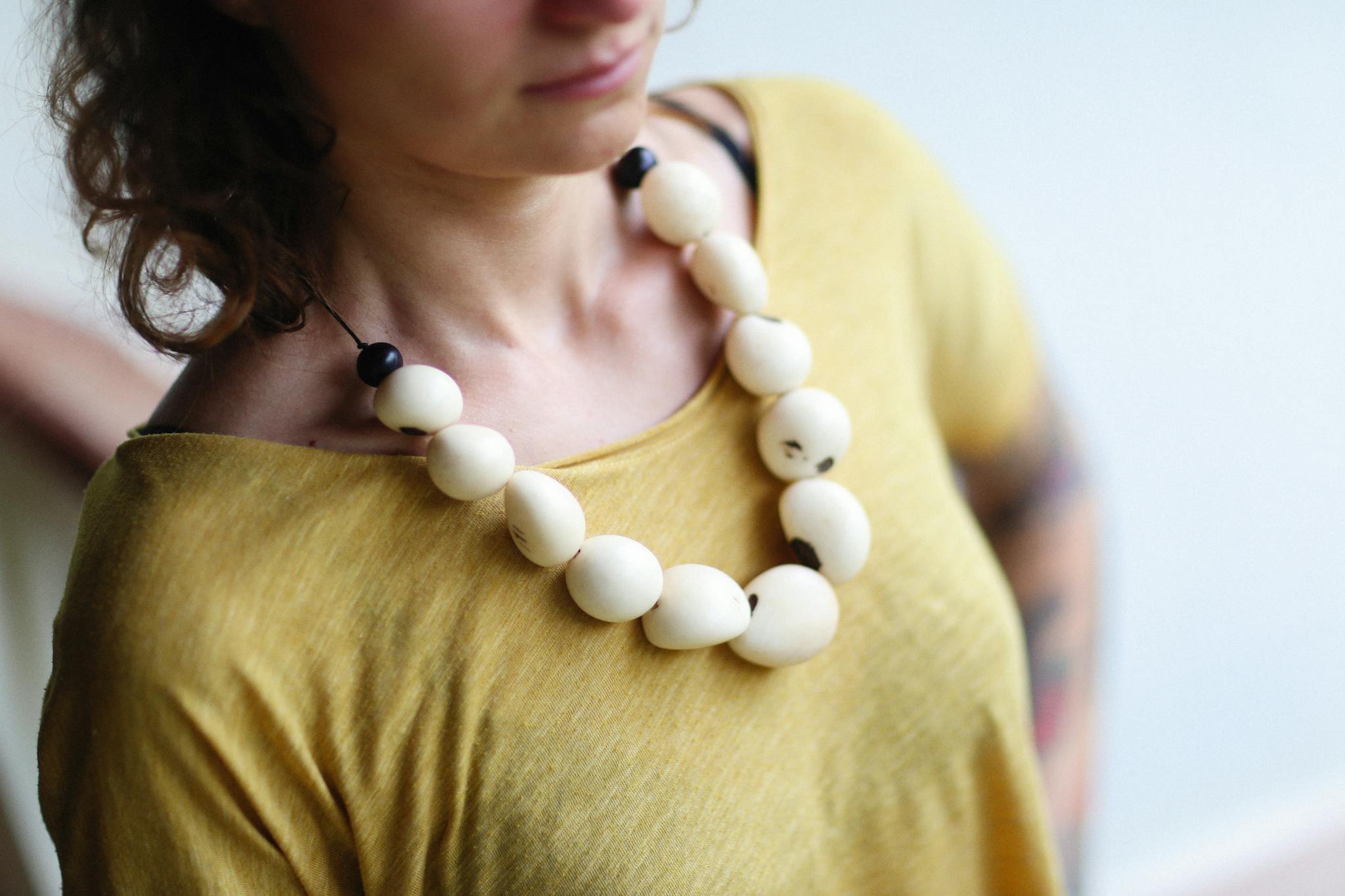 Close-up of a woman wearing a bold necklace with large beads.